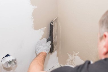 Duvarda sıva yapan inşaatçı işçilerin eli. Tadilat işçilerinin elleri duvarın alçıya alınması. İnşaat işleri tamamlanıyor. Spatül duvarı ile aynı hizada.