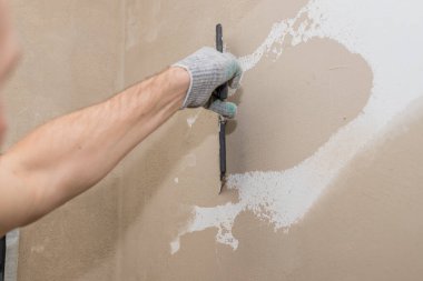 Bir spatula ile el, macun katmanı uygulama süreci. Dairelerin tadilatı. Duvarları onar. Reklam ve metin için boş alan.