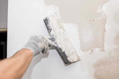 Metal spatula ile işlenmiş beton bir duvar. Bir macun katmanı uygulama süreci. Dairelerin tadilatı. Duvarları onar. Reklam ve ders için boş alan. Yaşam alanlarının tamiri..