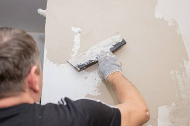 Metal spatula ile işlenmiş beton bir duvar. Bir macun katmanı uygulama süreci. Dairelerin tadilatı. Duvarları onar. Reklam ve ders için boş alan. Yaşam alanlarının tamiri..