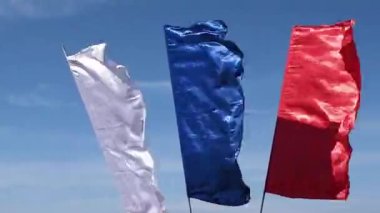 Rusya 'nın ulusal bayrağı, rüzgarlı bir günde gökyüzüne karşı ayrı bayrak direkleri üzerinde dalgalanan mavi bir gökyüzüne karşı dalgalanmaktadır..