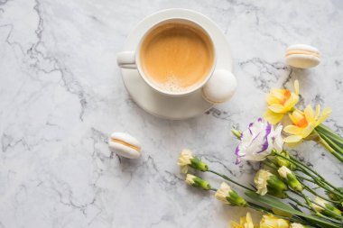 Beyaz fincanlı kurabiyeler, mermer arka planda parlak güzel çiçekler. Kadınlar için güzel bir kahvaltı. Bahar kavramı. Boşluğu kopyala