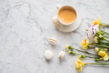 Beyaz fincanlı kurabiyeler, mermer arka planda parlak güzel çiçekler. Kadınlar için güzel bir kahvaltı. Bahar kavramı. Boşluğu kopyala