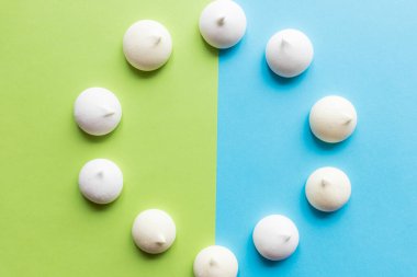 Mavi ve yeşil arka planda Meringue tatlısını daire içine alın. Fırın ürünü. Yukarıdan bak, düz kat. Zephyr, Küçük çok renkli meringu.Pop Sanat Rengi