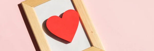 Red heart in wooden frame ,decoration on pink background. Love concept. romantic symbol of valentines day for background use. Concept of love, romance, and passion. Minimal Valentine concept.web — Stockfoto