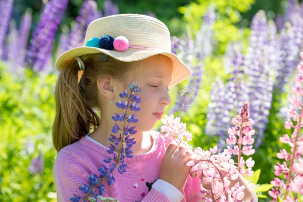 Beautiful cute girl in pink dress and hat in a field of flowers.Happy childhood. Closeup portrait of face of a cute little girl. Summer holidays and vacations — Foto Stock