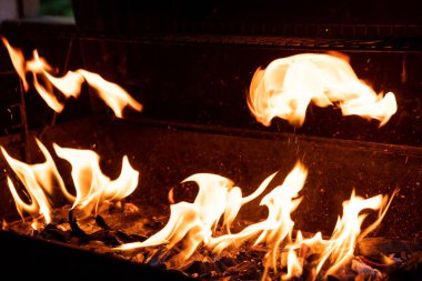 Sıcak barbekü ızgarası ve yanan ateş. Daha fazla barbekü, ızgara yemek, alevler ve ateş görebilirsiniz. Siyah Arkaplanda Ateşin Alevleri Olan Boş Kömür Izgarası. Yaz Açık Barbekü Partisi
