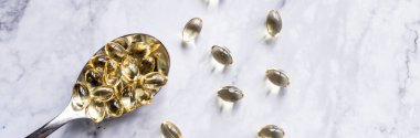 Kaşık üzerindeki balık yağı kapsülleri mermer zeminde izole edilmiş. Sağlıklı vitaminler, takviyeler, Omega 3. Sağlıklı yaşam tarzı. Boşluğu kopyala. Web pankartı