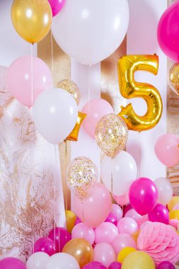 Çocuk doğum günü süslemeleri 5 yıl, beyaz pembe hava balonları. Parti dekorunda 5 numaralı büyük altın top. Bayram, yıldönümü, doğum günü için parlak karşılama bölgesi.