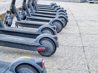 Otoparkta arka arkaya elektrikli scooterlar. Şehir bisikleti kiralama sistemi, sokakta kamu malı scooter 'lar. Kaldırımda kiralık modern eko elektrikli şehir scooterları. Alternatif turizm