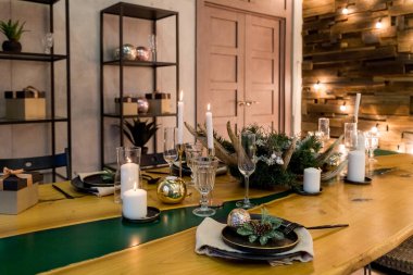 Noel için sade dekorasyonlu şenlik masası. Yeni yıl tatilleri, kutlamalar, modern iç tasarımlardaki dekorasyonlar. Sofra takımı, eko tarzı, mumlar ve sıcak ateş ve kozalaklı brunch.