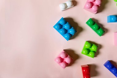 Pembe arka planda renkli plastik bloklar, metin için kopyalama alanı. Düz yatıyordu. Üst düzey çocuk inşaat seti. Geometrik şekilli çocuk binası. Öğrenim ve eğitim kavramı.
