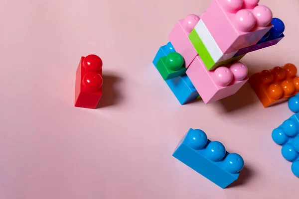 Blocos de construção de plástico colorido em fundo rosa, espaço de cópia para texto. Deitado. Conjunto de construção Top view.childrens. Edifício infantil com formas geométricas. Conceito de aprendizagem e educação. — Fotografia de Stock