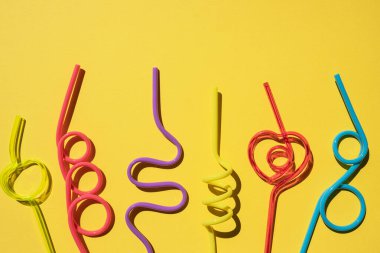 Sarı arka planda izole edilmiş Spiral renkli kokteyl tüpleri. Partide saman içiliyor..