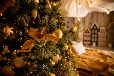 Bulanık, ışıl ışıl ve peri arkaplanda süslenmiş Noel ağacı. Parlak altın takılar, toplar, xmas süsleri ve parlak sıcak ışıklar, çelenklerle süslenmiş köknar ağacı dalları..