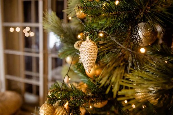 点缀在模糊的、闪闪发光的和仙境中的圣诞树。节庆的枞树枝条，上面有闪亮的金黄色的灌木、球、圣诞装饰品和明亮的暖灯、花环. — 图库照片