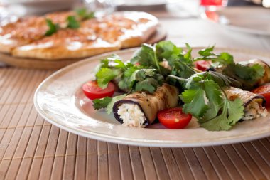 Peynirle doldurulmuş lezzetli patlıcan ruloları. Aperatif. Krem peynirle doldurulmuş patlıcan, sarımsak ve fındık, domates.