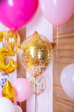 Resepsiyonda pembe ve beyaz balonlar. Helyum dolu balonlar, beyaz ve altın renkler, altın kurdeleler. Doğum günlerini ve diğer bayramları kutlamak için gerekli bir aksesuar olarak uçan toplar..