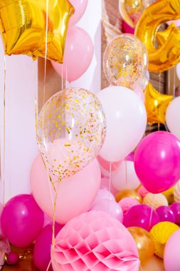 Resepsiyonda pembe ve beyaz balonlar. Helyum dolu balonlar, beyaz ve altın renkler, altın kurdeleler. Doğum günlerini ve diğer bayramları kutlamak için gerekli bir aksesuar olarak uçan toplar..