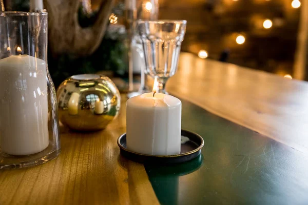 Apparecchiatura della tavola di Natale in stile rustico con candele, piatti, bicchieri e decorazioni eco su tavolo festivo in legno.Decorazioni di Capodanno con rami di abete, palle d'oro, pigne. Vacanze invernali accoglienti. — Foto Stock
