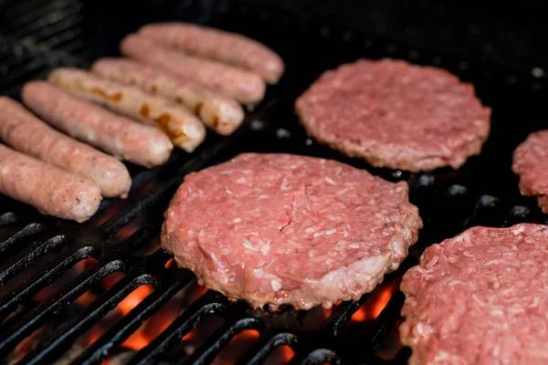 Hamburgers on Grill with Dancing Flames Cooked to Perfection.A closeup of some fresh and juicy hamburgers cooking on the grill.Beef burgers being cooked — Stock Photo, Image