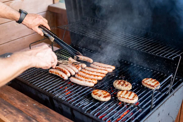 Grillowanie w letni weekend. Świeże mięso przygotowuje się na grillu.Człowiek ręka na grillu przygotowuje mięso na przyjęcie ogrodowe.Gotowanie mięsa na płomień. Pieczeń — Zdjęcie stockowe