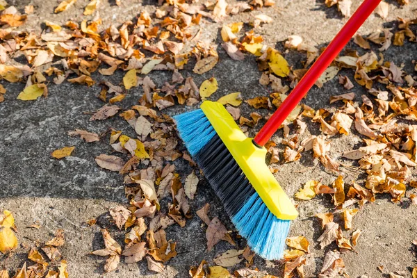 Barrer las hojas caídas del suelo del jardín para su reciclaje durante la temporada otoñal de otoño.El hombre escoba la calle para recoger las hojas caídas secas. — Foto de Stock