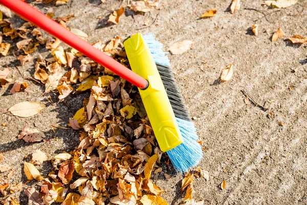 Het vegen van de gevallen bladeren uit de tuin voor recycling in het najaar seizoen.Man bezweert de straat om droge gevallen bladeren te verzamelen. — Stockfoto