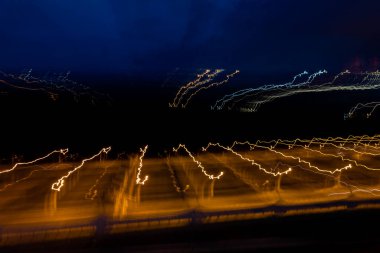 Gece lambasının sokaktaki soyut arkaplanı, uzun pozlu çekim. Soyut hareket hızı. Siyah arkaplandaki ışıkların uzun pozlu fotoğrafı.