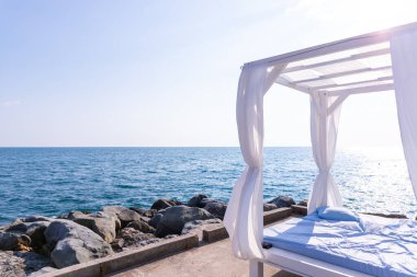 Bulutlu bir günde deniz arka planına sahip sahildeki pavyon - seyahat ve tatil konseptleri. Lüks kumsal çadırları. Beyaz perdeli romantik çardak örtüleri. Bungalov denize yakın. Uzayı kopyala