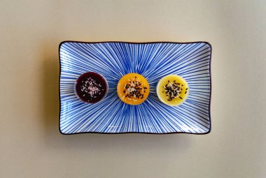 Üçlü bir peynirli kek tabakta çeşitli tatlarda tatlılar sunar.