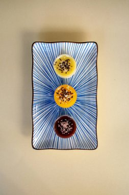 Tabak portresindeki çeşitli aromalı mini cheesecake tatlılarından oluşan üçlü.