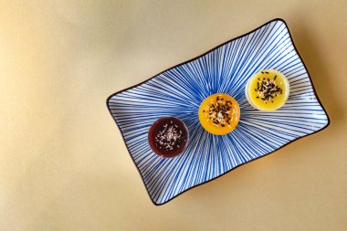 Mini peynirli kek üçlüsü tabağın sağ tarafında çeşitli tatlar sunar.