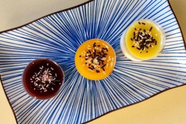 Mini peynirli kek üçlüsü tabakta çeşitli aromalı tatlılar sunar.