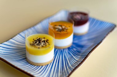 Aydınlıktan koyu renklere bir tabakta servis edilen mini cheesecake üçlüsü.