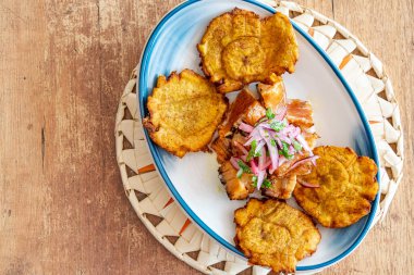 Soğan ve limon soslu dilimlenmiş biftekle servis edilen bir tabak kızarmış muz.