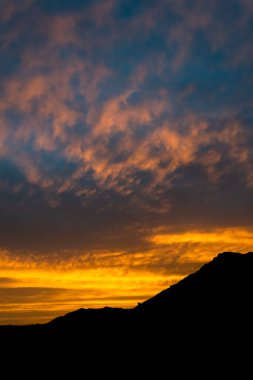İspanya 'nın Marbella kasabasının üzerinde dağ silueti olan alev sarısı bir günbatımı. 