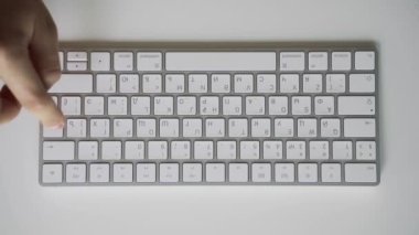 Erkek eller yavaş yavaş beyaz bir bilgisayar klavyesine yazmayı öğreniyor. Tablo üstü görünümü.