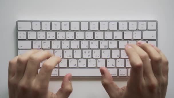 Manos masculinas escribiendo en un teclado de computadora blanco. Mesa vista superior. — Vídeos de Stock