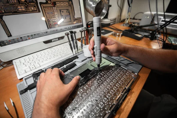 Técnico de mano reparando el portátil portátil con un destornillador Imagen de archivo