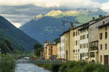 Tirano, Sondrio, Valtellina, Lombardy, İtalya: Adda nehri kıyısında arka planda dağlar olan eski evler