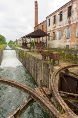 Cascade along the Naviglio Pavese, canal from Milan to Pavia, Lombardy, Italy, with historic buildings