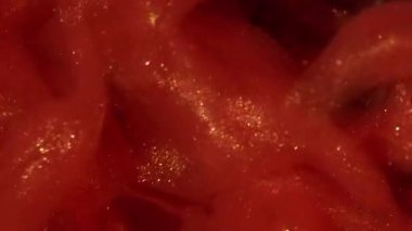 Parıltı yayılıyor. Boya girdabı. Parıldayan sanat parçacıkları su akar. Canlı renk emülsiyonu patlaması kırmızı turuncu soyut arkaplan.