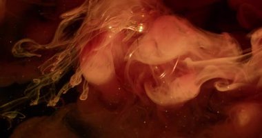 Bulut sıçraması. Mürekkep lekesi bulanıklığı. Cam ampulüne renkli sıvı duman karışımı. Işıldayan bokeh ışıltısı, turuncu akıntı, soyut siyah arka plana yayılıyor..