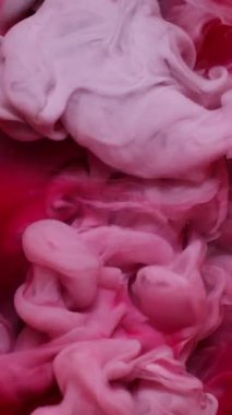Dikey video. Sıvı pigmenti. Duman mürekkebi. Odaklanmamış kırmızı pembe renkli su girdabı akrilik soyut sanat arka planında akıyor.