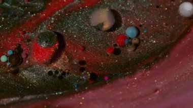 Shimmer döküldü. Suyu boya. Odaklanmamış kırmızı mavi damlacık simli yağ akrilik sıvısı soyut siyah arka planda yüzüyor.