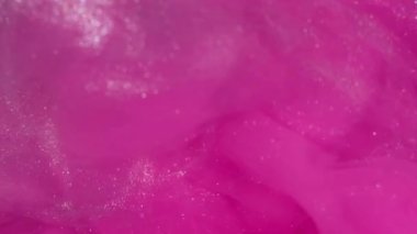 Parıltı yayılıyor. Boya girdabı. Parıldayan sanat parçacıkları su akar. Neon rengi emülsiyon patlaması pembe beyaz gümüş soyut arkaplan.