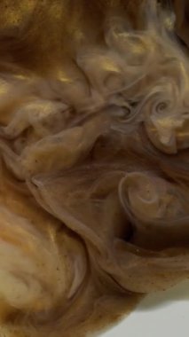 Dikey video. Dalga mürekkebi. Sıvı doku. Odaklanmamış sarı bronz renkli su tanecikleri soyut sanat arkaplanda akan buhar sıvısı beyaz zemin.