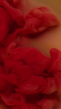 Dikey video. Bulut dalgası. Boya karışımı. Odaklanmamış kırmızı kırmızı renkli su dokusu soyut sanat arka planında yüzen akrilik parlak buhar.