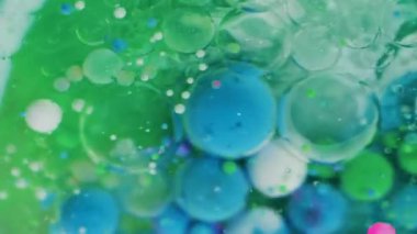 Jel mürekkebi. Yağlı boya balonu. Yeşil sıvı içinde renkli akrilik damlalar. Sanat dalgası fizz parçacıkları soyut odaklanmış arkaplanı karıştırır.